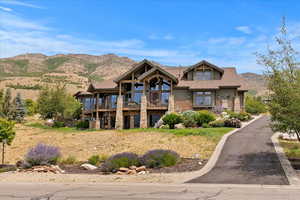 View of front facade with a mountain view, stone siding, and a balcony