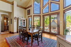 Dining space with high vaulted ceiling, walnut wood floors, and arched walkway leading into en-suite primary