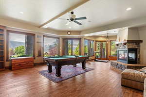 Recreation room featuring wood finished floors, billiards, recessed lighting, a stone fireplace, and a ceiling fan