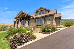 Craftsman-style home with stone siding and a shingled roof