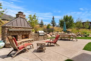 Back patio with stone fireplace and and grill. Beautifully landscaped
