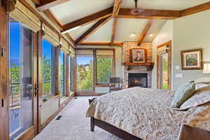 Main level en-suite primary bedroom with door to front deck, stone fireplace, large windows for views and door to hot tub deck.