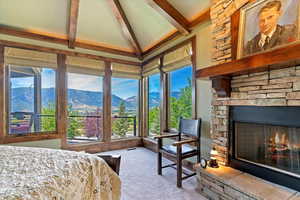 Primary en-suite bedroom with a mountain views large windows, stone fireplace. Door to front deck.