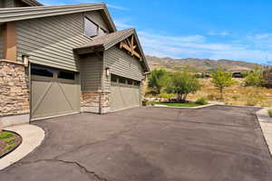 View of side of home featuring stone siding, asphalt driveway, and a mountain view