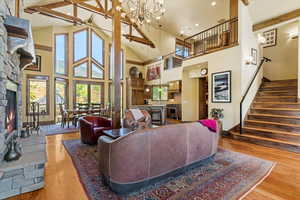 Living area with a stone fireplace, high vaulted ceiling, and hand blown chandelier made in Park City. Beautiful large windows allow for views and natural light.