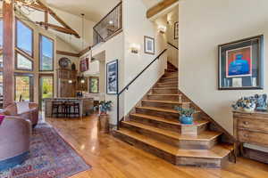 Stairs with high vaulted ceiling and wood finished floors lead to the second floor en-suite primary and office space