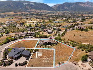 Aerial view of residential area featuring property parcel outlined and a mountain backdrop