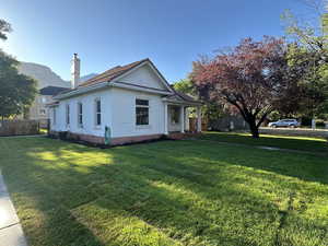 View of side of home featuring a chimney, a porch, and brick siding