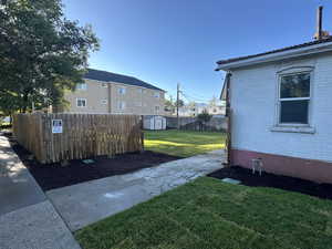 Fenced backyard featuring a storage unit