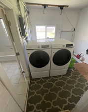 Laundry room with light tile patterned floors, electric panel, and washer and clothes dryer