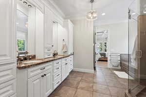 Ensuite bathroom with a stall shower, double vanity, crown molding, light tile patterned floors, and recessed lighting