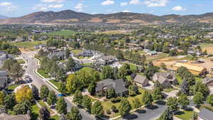 Aerial view of property and surrounding area featuring mountains and nearby suburban area