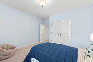 Carpeted bedroom featuring baseboards and a closet