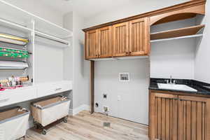 Laundry room with light wood-style flooring, hookup for a washing machine, cabinet space, and electric dryer hookup