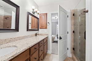 Ensuite bathroom featuring a shower stall, double vanity, light tile patterned flooring, and a chandelier