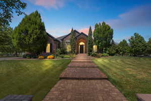 View of front facade featuring a lawn and brick siding