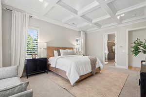 Carpeted bedroom featuring beam ceiling, coffered ceiling, ensuite bathroom, and crown molding