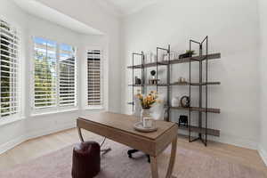 Office area with crown molding and light wood-style flooring