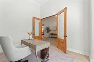 Office area with light wood-style floors, french doors, and ornamental molding