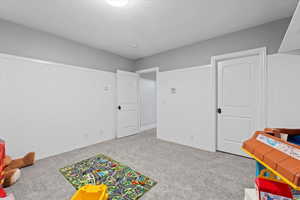 Rec room featuring carpet and a textured ceiling