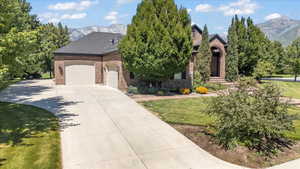 View of front of house with brick siding, a mountain view, an attached garage, driveway, and a front yard
