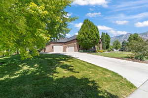Obstructed view of property with a front yard, concrete driveway, an attached garage, a mountain view, and brick siding