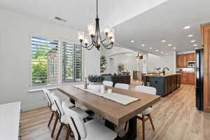 Dining area featuring light wood-style flooring, recessed lighting, arched walkways, and a chandelier