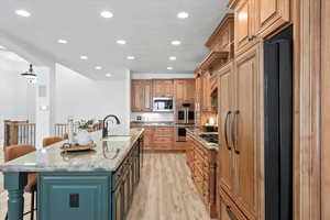 Kitchen featuring a breakfast bar, light stone countertops, stainless steel appliances, recessed lighting, and a large island