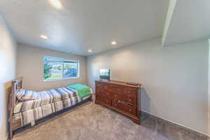 Carpeted bedroom with a textured ceiling and recessed lighting
