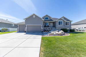 Craftsman-style house with stone siding, a front lawn, and covered porch
