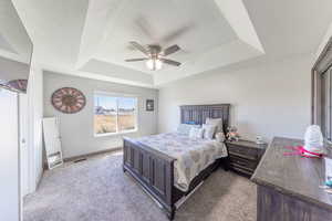 Carpeted bedroom with a tray ceiling, a ceiling fan, and a textured ceiling