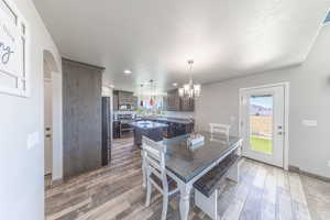 Dining area with arched walkways, light wood-style floors, a chandelier, recessed lighting, and a textured ceiling