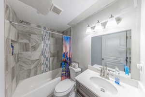 Bathroom featuring shower/bathtub combination with curtain, vanity, and a textured ceiling