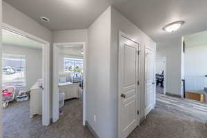 Corridor featuring light colored carpet and a textured ceiling