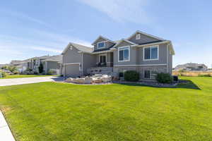Craftsman inspired home featuring stucco siding, covered porch, a garage, driveway, and a front yard