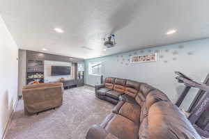 Living room with light colored carpet, a textured ceiling, and recessed lighting