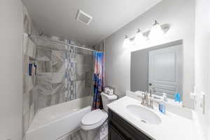 Bathroom featuring shower/bathtub combination with curtain, vanity, and a textured ceiling