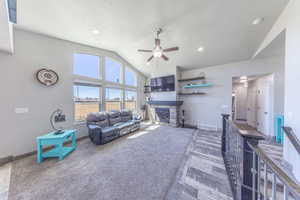 Carpeted living area with a fireplace, a ceiling fan, high vaulted ceiling, and recessed lighting