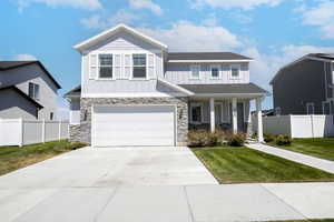 Craftsman house featuring board and batten siding, a garage, a porch, driveway, and stone siding