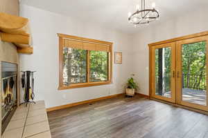 Unfurnished dining area with wood finished floors, a glass covered fireplace, healthy amount of natural light, and a chandelier