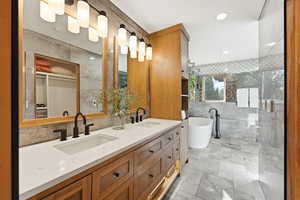 Bathroom with double vanity, a freestanding tub, a shower stall, tile walls, and recessed lighting