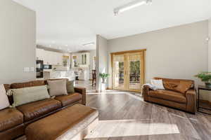 Living area featuring french doors, wood finished floors, healthy amount of natural light, and rail lighting