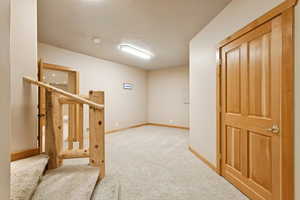Corridor featuring light colored carpet and baseboards