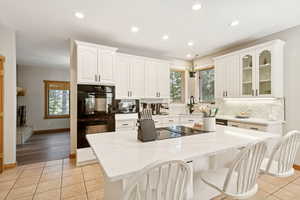 Kitchen featuring a breakfast bar area, light stone counters, light tile patterned flooring, recessed lighting, and backsplash