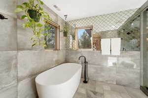 Full bath with tile walls, a freestanding bath, and a stall shower
