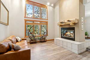 Living room with a high ceiling, a fireplace, and wood finished floors
