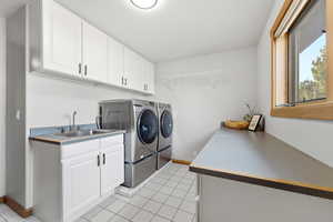 Laundry area with separate washer and dryer, cabinet space, and light tile patterned floors