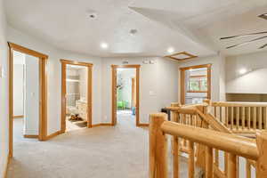 Hall with an upstairs landing, light colored carpet, recessed lighting, and a textured ceiling