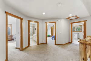 Hallway with light colored carpet and recessed lighting