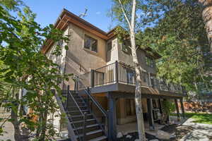 Rear view of house with a patio area, stucco siding, a wooden deck, and stairs